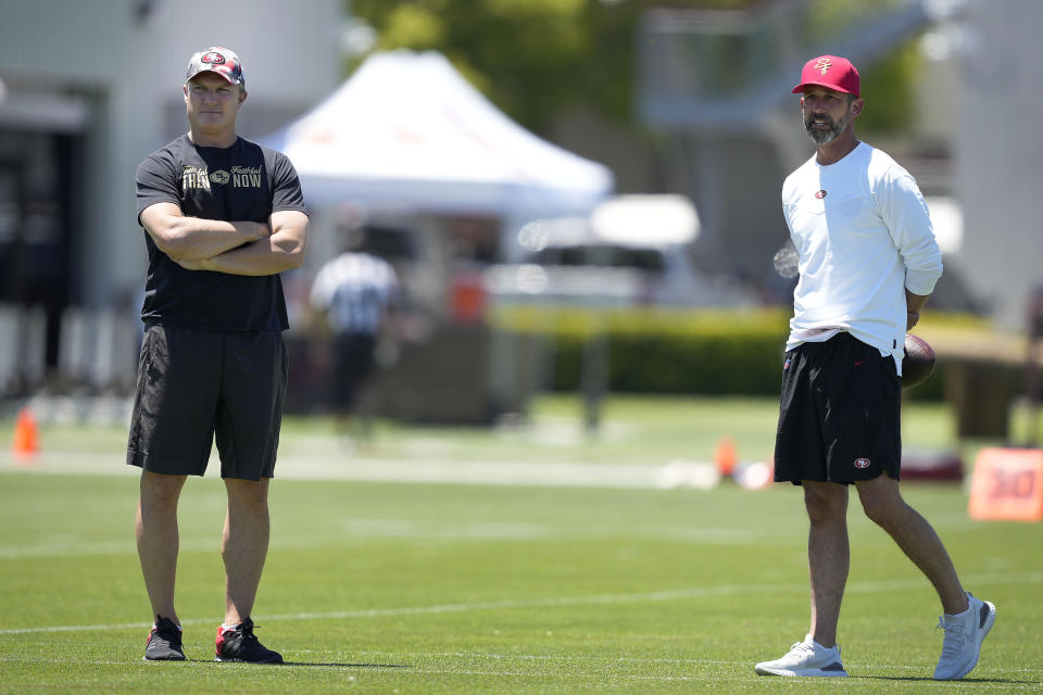 FILE - San Francisco 49ers general manager John Lynch, left, and head coach Kyle Shanahan watch players warm up at the NFL football team's practice facility in Santa Clara, Calif., on June 1, 2022. Shanahan started camp Tuesday, July 26, 2022, by removing any pretense of a quarterback competition in San Francisco by unequivocally stating what had seemed obvious all offseason that Trey Lance will take over as starter a year after being drafted third overall. (AP Photo/Tony Avelar, File)