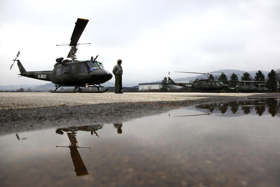 An army pilot stands in front of a military Huey II helicopter during a ceremony in Rajlovac barracks near the capital Sarajevo, Bosnia, Friday, Dec. 10, 2021. The Bosnian Army received four US Huey II helicopters as part of US government support. (AP Photo)