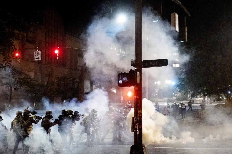 Federal agents use crowd control munitions to disperse Black Lives Matter protesters near the Mark O. Hatfield United States Courthouse on Monday, July 20, 2020, in Portland, Ore. Officers used teargas and projectiles to move the crowd after some protesters tore down a fence fronting the courthouse. (AP Photo/Noah Berger)