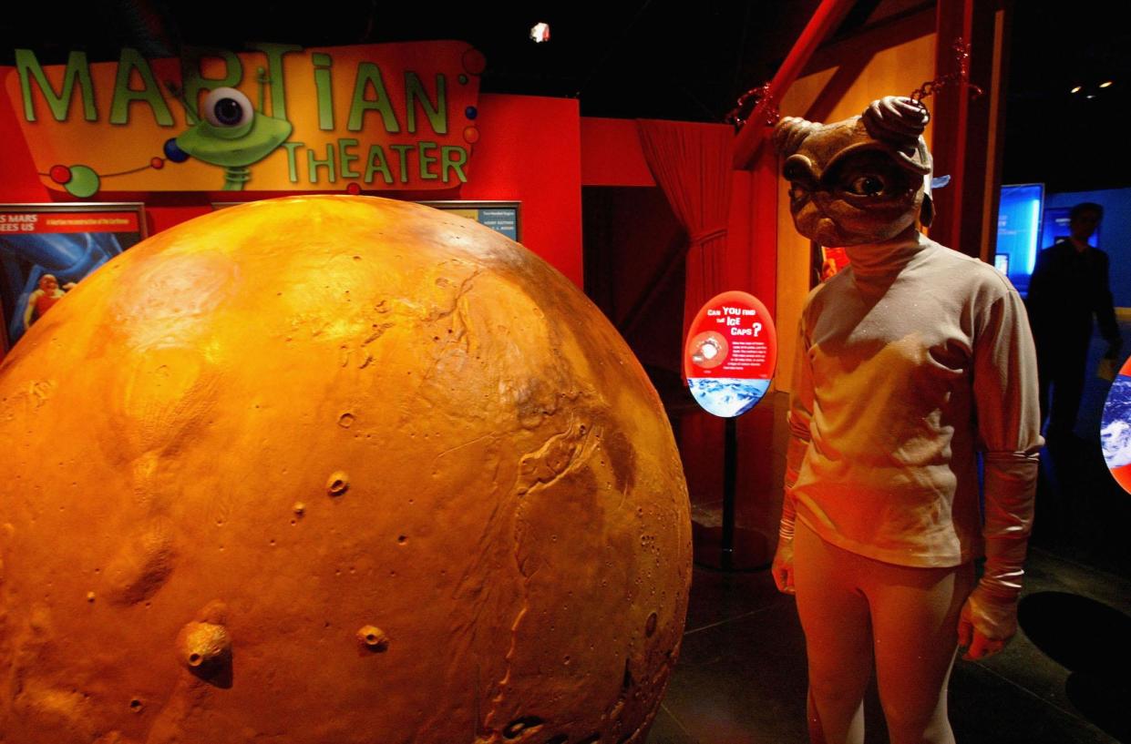 person dressed as an alien attends the Mars Encounter exhibit at the Chabot Space and Science Center August 26, 2003 in Oakland, California. Hundreds of astronomy enthusiasts visited the Chabot Space Center in hopes of viewing the red planet Mars through high-powered telescopes: Justin Sullivan/Getty Images