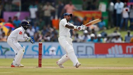 Cricket - Sri Lanka v India - First Test Match - Galle, Sri Lanka - July 26, 2017 - India's cricketer Shikhar Dhawan plays a shot next to Sri Lanka's wicketkeeper Niroshan Dickwella. REUTERS/Dinuka Liyanawatte