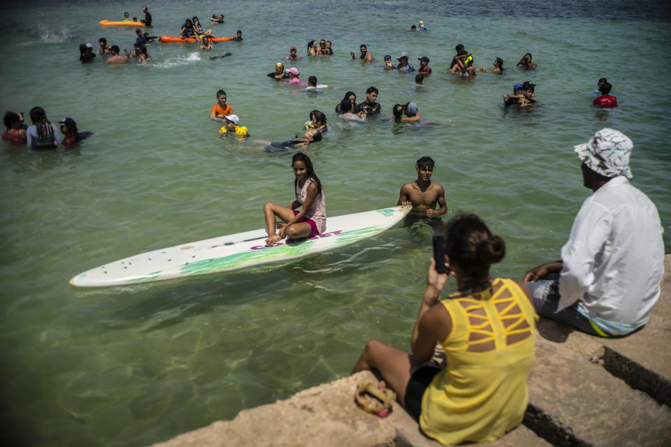 La gente disfruta el día en la Playa del Salado en Caimito, provincia de Artemisa, Cuba, el miércoles 15 de julio de 2020. Por las menores restricciones gubernamentales y la ola de calor que azota a la isla, miles de cubanos están abarrotando las playas. Después de una cuarentena de más de tres meses, la tasa de infección por COVID-19 sigue siendo extremadamente baja. (AP Foto/Ramón Espinosa)