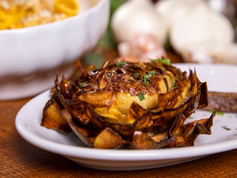 roman style fried artichoke appetizer on a wooden table with other dishes