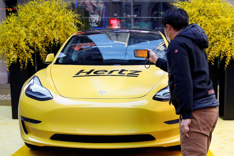 FILE PHOTO: A man photographs a Hertz Tesla electric vehicle displayed during the Hertz Corporation IPO at the Nasdaq in New York