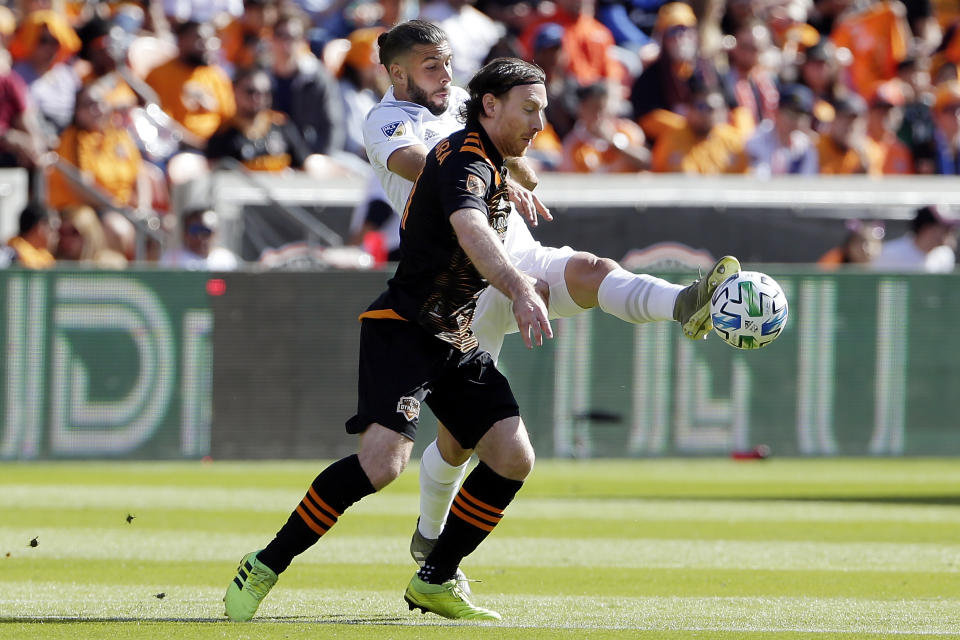 Los Angeles Galaxy defender Emiliano Insúa, back, kicks away the ball away from Houston Dynamo midfielder Tommy McNamara during the first half of an MLS soccer match Saturday, Feb. 29, 2020, in Houston. (AP Photo/Michael Wyke)