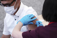 An employee of beverage maker Suntory takes a Moderna COVID-19 vaccine shot at their office building as the company began its workplace vaccination Monday, June 21, 2021, in Tokyo. Thousands of Japanese companies began distributing COVID-19 vaccines to workers and their families Monday in an employer-led drive reaching more than 13 million people that aims to rev up the nation's slow vaccine rollout. (AP Photo/Eugene Hoshiko)