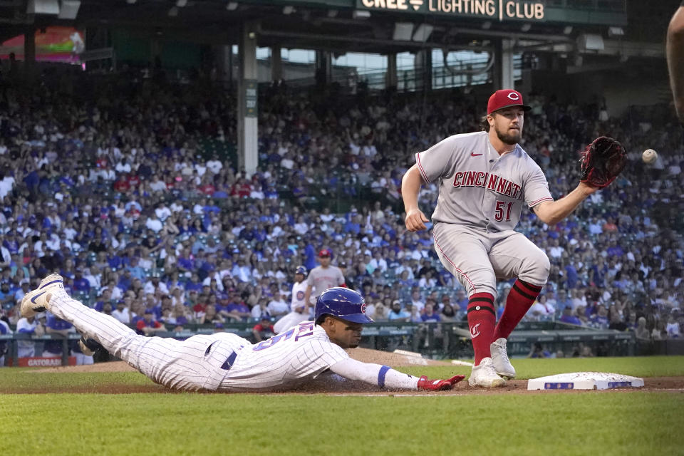 Chicago Cubs' Christopher Morel dives safely in to first on an infield single as Cincinnati Reds starting pitcher Graham Ashcraft fields the throw from first baseman Joey Votto during the second inning of a baseball game Thursday, June 30, 2022, in Chicago. (AP Photo/Charles Rex Arbogast)