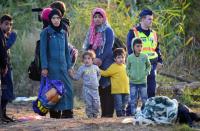A group of migrant women and children escorted by police wait at a collector point near Roszke village at the Hungarian-Serbian border on August 28, 2015