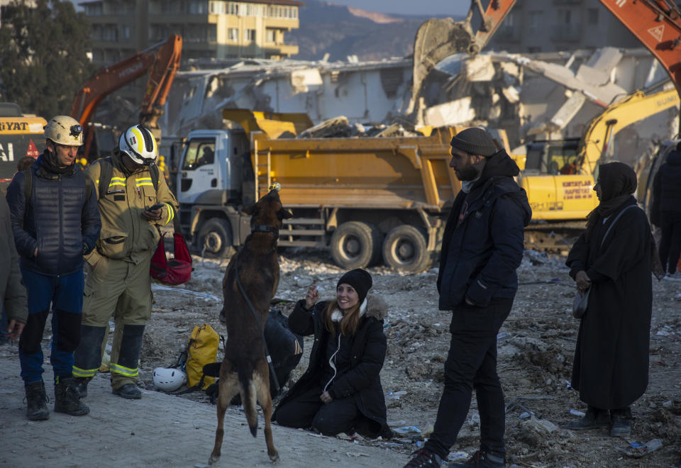 A woman plays with a sniffer dog as rRescue workers continue the search for victims of the earthquake in Antakya, Turkey, Saturday, Feb. 11, 2023. Rescue crews on Saturday pulled more survivors, including entire families, from toppled buildings despite diminishing hopes as the death toll of the enormous quake that struck a border region of Turkey and Syria five days continued to rise. (AP Photo/Lefteris Pitarakis)