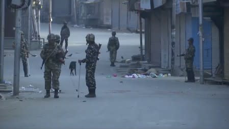 Security personnel patrol a street in Srinagar