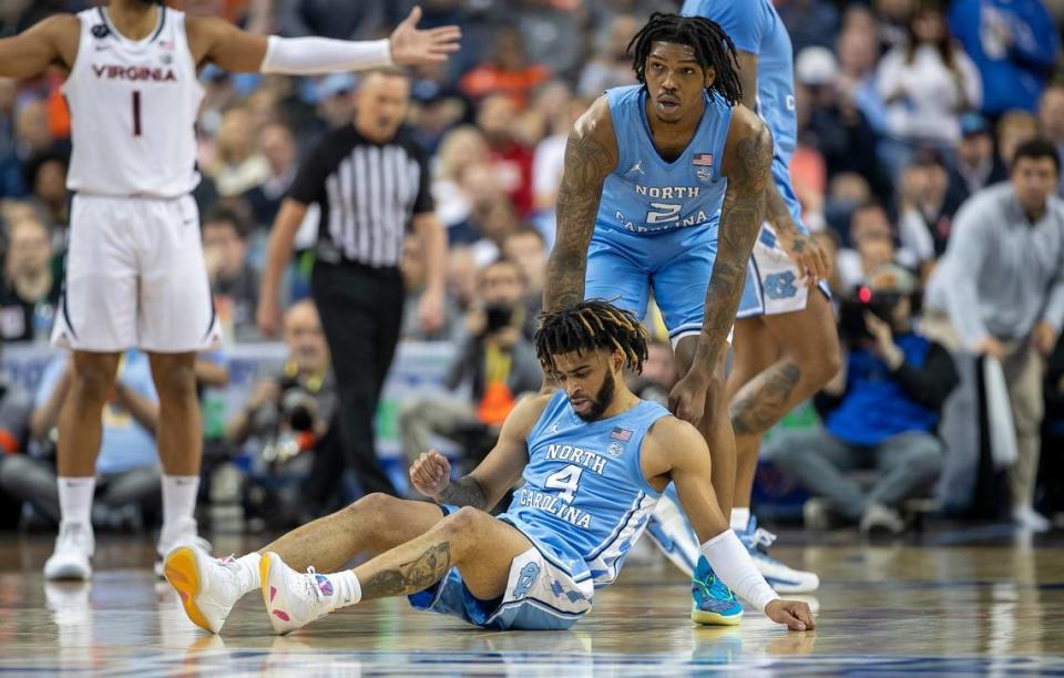 North Carolina’s Caleb Love (2) helps teammate R.J. Davis (4) to his feet after a collision in the second half against Virginia during the third round of the ACC Tournament on Thursday, March 9, 2023 at the Greensboro Coliseum in Greensboro, N.C. Robert Willett/rwillett@newsobserver.com