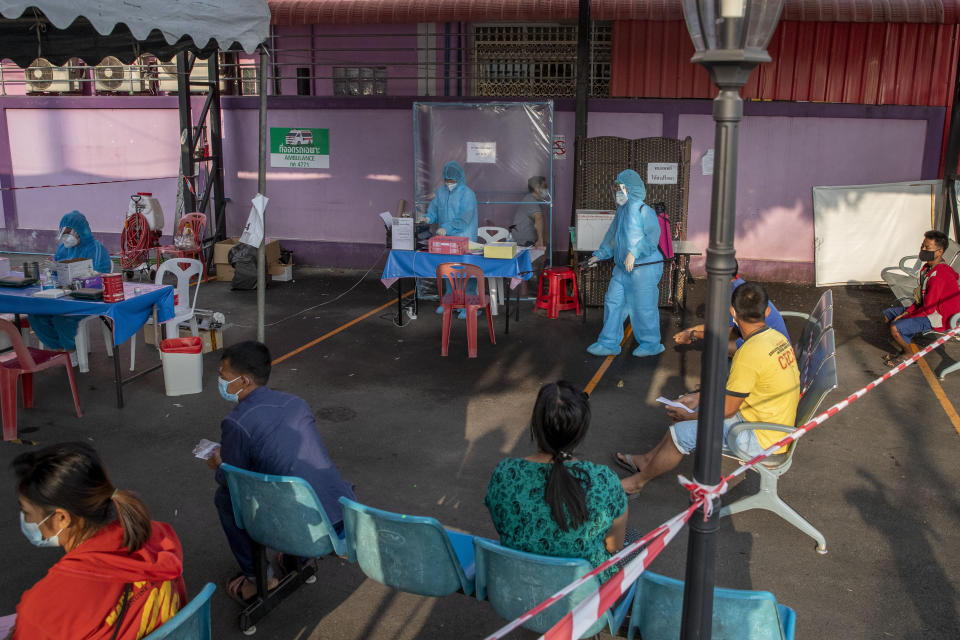 Migrant workers and their families gather at an outdoor screening center for COVID-19 in Samut Sakhon, South of Bangkok, Thailand Monday, Jan. 4, 2021. For much of 2020, Thailand had the coronavirus under control. After a strict nationwide lockdown in April and May, the number of new local infections dropped to zero, where they remained for the next six months. However, a new outbreak discovered in mid-December threatens to put Thailand back where it was in the toughest days of early 2020. (AP Photo/Gemunu Amarasinghe)