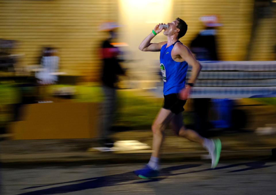 A runner hydrates using a water stop along the 2021 Oklahoma City Memorial Marathon route in northeast Oklahoma City.