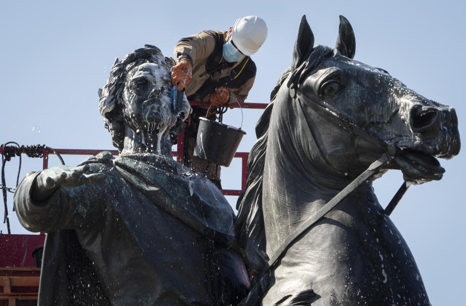 A worker wearing a face mask to protect against coronavirus washes a city landmark, the equestrian statue of the Russian Tsar Peter the Great known as the Bronze Horseman by French sculptor Etienne Maurice Falconet, in St.Petersburg, Russia, Tuesday, May 26, 2020. (AP Photo/Dmitri Lovetsky)
