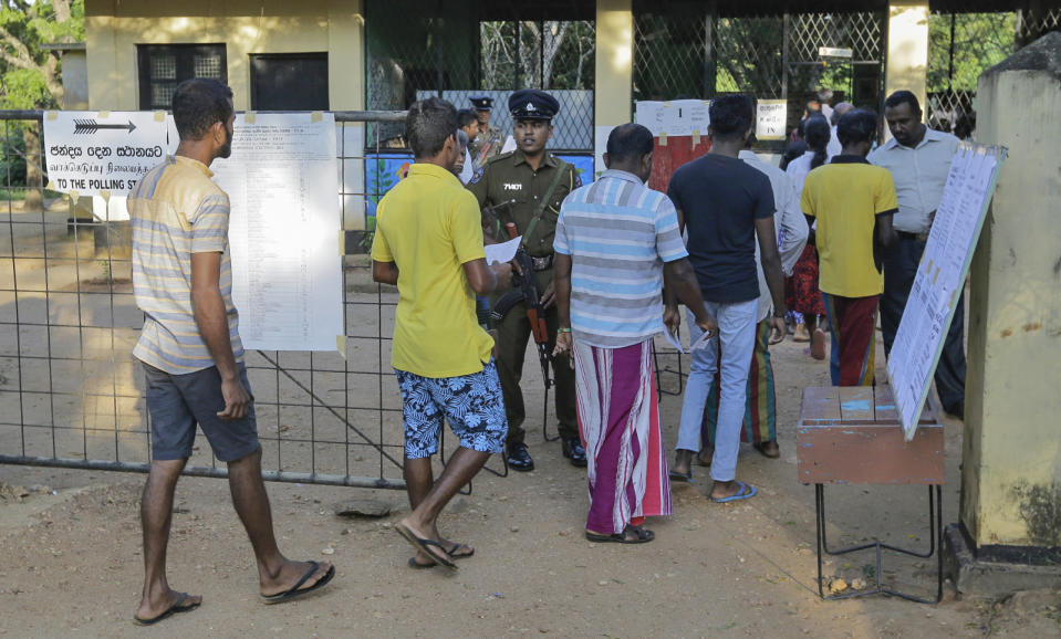 Sri Lankans wait in a queue to cast their votes at a polling station after casting his vote in Weerawila, Sri Lanka, Saturday, Nov. 16 , 2019. A convoy of buses carrying Muslim voters traveling in northern Sri Lanka was attacked by gunfire and stones, and blocked by burning tires, around midnight on Saturday hours before polls opened in Sri Lanka’s presidential election, according to Colombo-based Centre for Monitoring Election Violence. (AP Photo/Chamila Karunarathne )