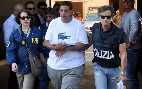 A US Federal Bureau of Investigation (FBI) officer (L) and Italian police officer (R) escort Thomas Gambino after he was arrested in Palermo during an police/FBI operation called 'New Connection' in Palermo on July 17, 2019 - Credit: AFP