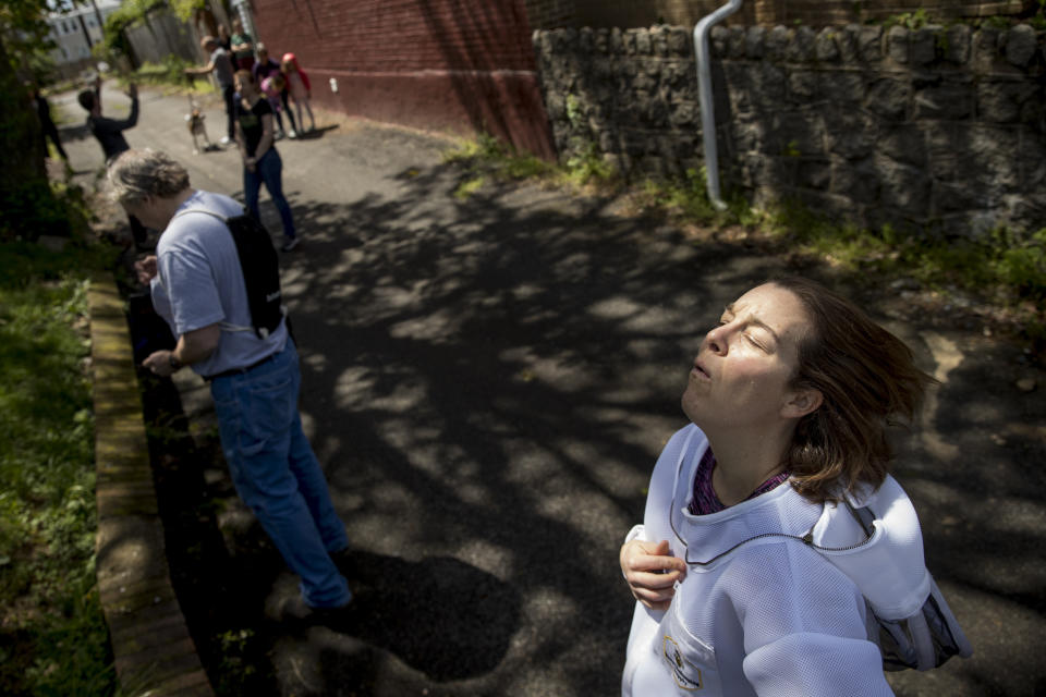 Beekeeper Erin Gleeson takes a deep breath as she takes off her mask after capturing a swarm of honey bees to relocate them to a bee hive, Friday, May 1, 2020, in Washington. The District of Columbia has declared beekeepers as essential workers during the coronavirus outbreak. If the swarm isn’t collected by a beekeeper, the new hive can come to settle in residential backyards, attics, crawlspaces, or other potentially ruinous areas, creating a stinging, scary nuisance. (AP Photo/Andrew Harnik)