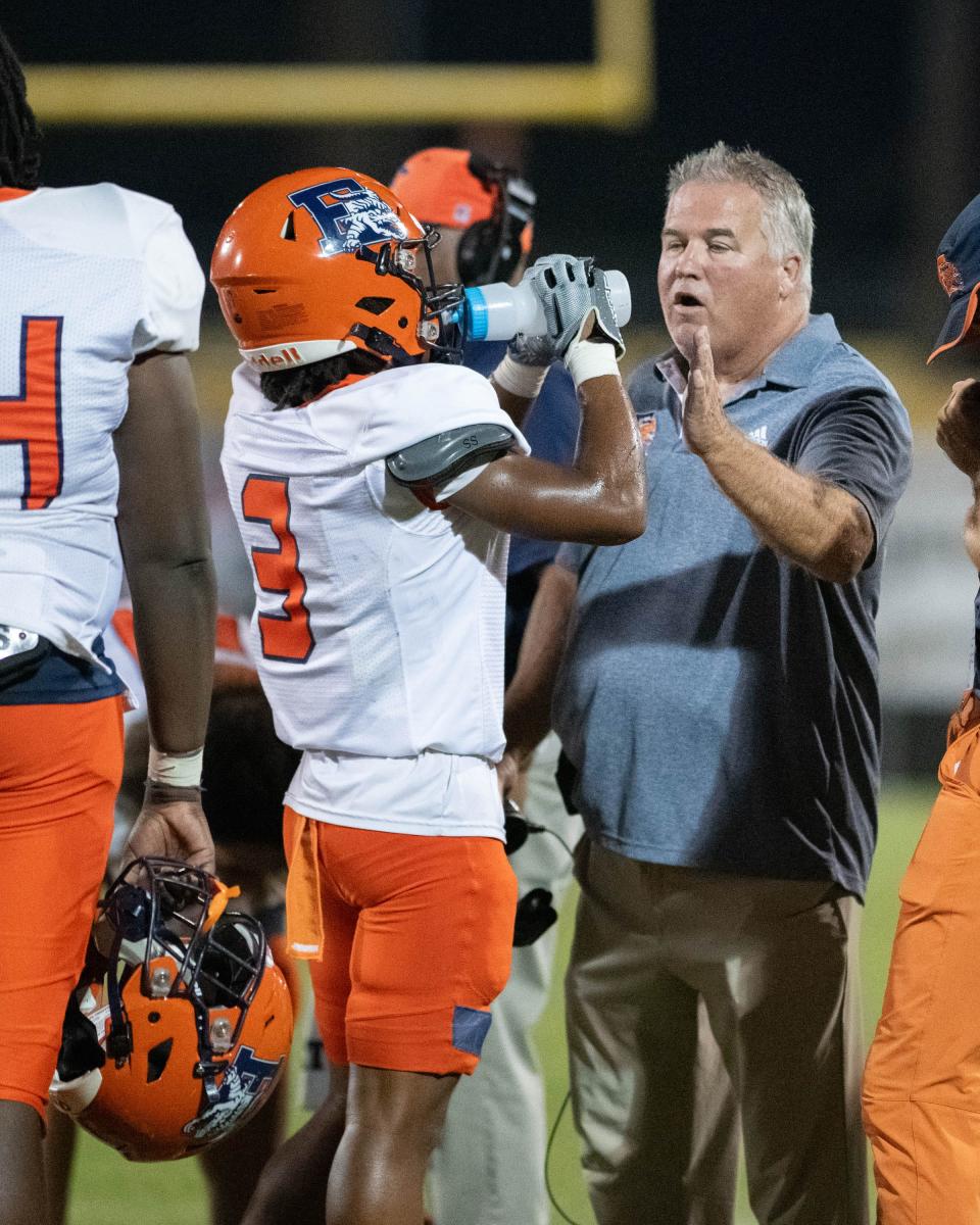 Gators head coach Mike Bennett talks with his players during a timeout in the Escambia vs Milton football game at Milton High School on Friday, Sept. 22, 2023.