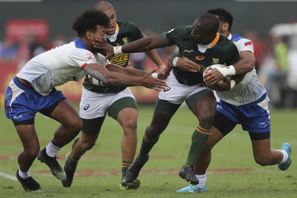 South Africa's Siviwe Soyizwapi runs with the ball as Samoa's players try to stop him during a semi final match of the Emirates Airline Rugby Sevens in Dubai, United Arab Emirates, Saturday, Dec.7, 2019. (AP Photo/Kamran Jebreili)