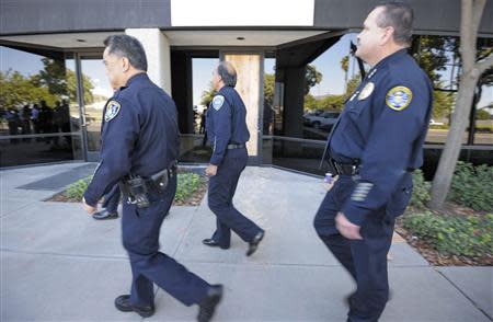 Law enforcement officials walk past a boarded up door to a warehouse that leads to a newly discovered drug smuggling tunnel in Otay Mesa area of San Diego, California October 31, 2013. REUTERS/Denis Poroy