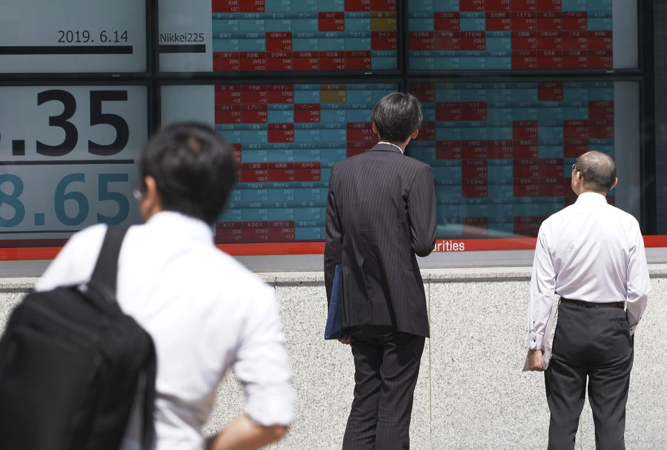 Pedestrians look at an electronic stock board showing Japan's Nikkei 225 index at a securities firm in Tokyo Friday, June 14, 2019. Asian shares were mixed Friday as investors weighed a variety of factors, including suspected attacks on two oil tankers in the strategic Strait of Hormuz and lingering worries about trade conflict between the U.S. and China. (AP Photo/Eugene Hoshiko)