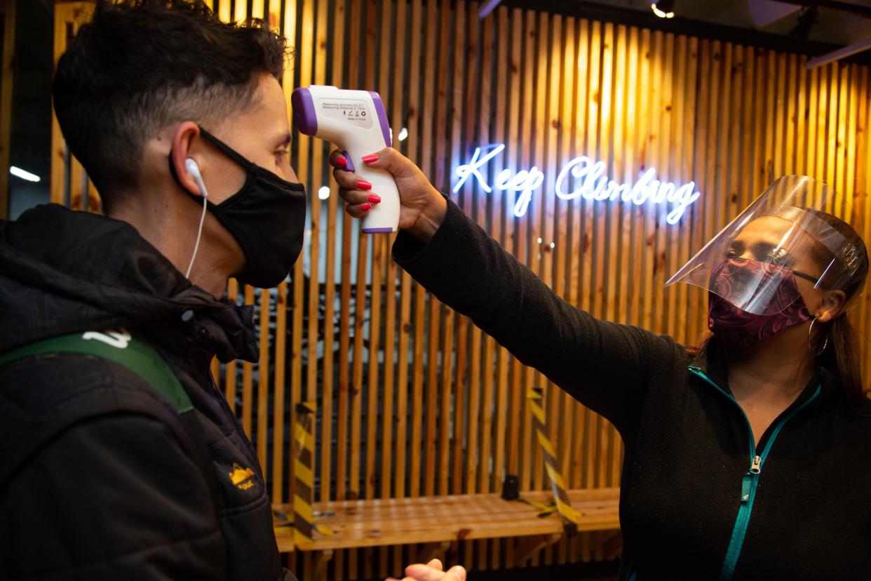 A man wearing a face mask has his temperature taken by a staff member wearing a face shield before entering an indoor climbing gym amidst the coronavirus (COVID-19) pandemic on July 15, 2020, in Sao Paulo, Brazil. The government of Sao Paulo updated its plan to reopen the economy and anticipated the return of gyms following social distance rules such as reduced opening hours, restricting the flow of people and maintaining hygiene standards.