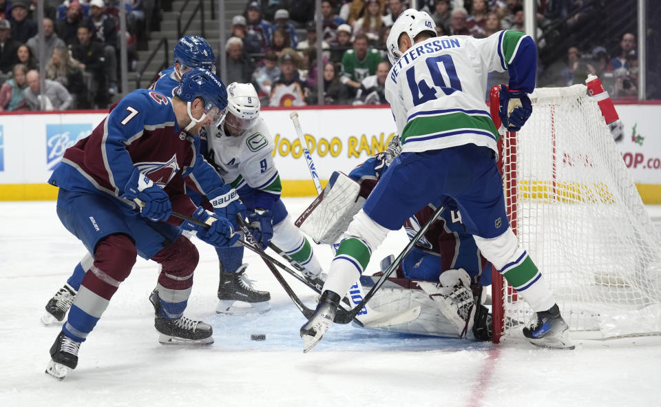 Colorado Avalanche defenseman Devon Toews, front left, vie for control of the puck with defenseman Cale Makar and Vancouver Canucks center J.T. Miller, back left, after Avalanche goaltender Alexandar Georgiev,stopped a shot by Vancouver center Elias Pettersson during the second period of an NHL hockey game Wednesday, Nov. 22, 2023, in Denver. (AP Photo/David Zalubowski)