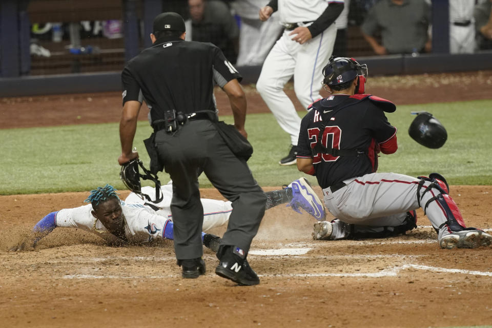 Miami Marlins Jazz Chisholm Jr. scores as Washington Nationals catcher Keibert Ruiz (20) is late with the tag in the tenth inning of a baseball game, Wednesday, June 8, 2022, in Miami. The Marlins defeated the Nationals 2-1. (AP Photo/Marta Lavandier)