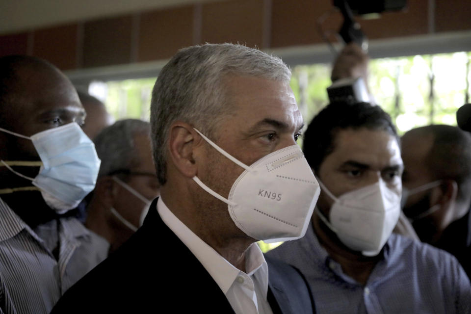 Wearing a mask as a precaution against the spread of the new coronavirus, Gonzalo Castillo, center, presidential candidate of the Dominican Liberation Party, arrives at a voting center during the presidential elections, in Santo Domingo, Dominican Republic, Sunday, July 5, 2020. (AP Photo/Tatiana Fernandez)