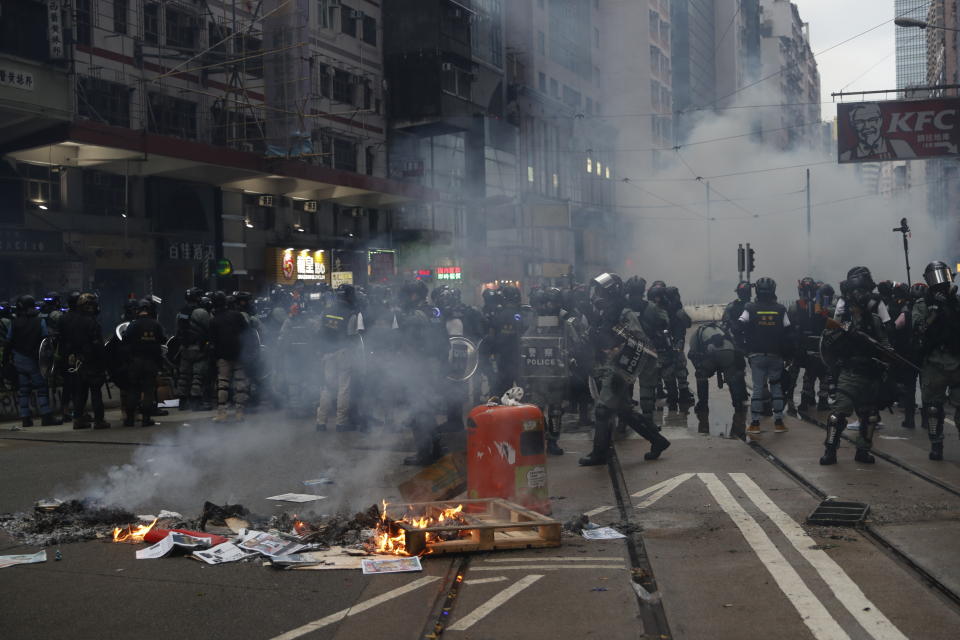 Police arrive as protestors burn garbage to block traffic in Hong Kong, Sunday, Oct. 6, 2019. Shouting "Wearing mask is not a crime," tens of thousands of protesters braved the rain Sunday to march in central Hong Kong as a court rejected a second legal attempt to block a mask ban aimed at quashing violence during four months of pro-democracy rallies. (AP Photo/Vincent Thian)