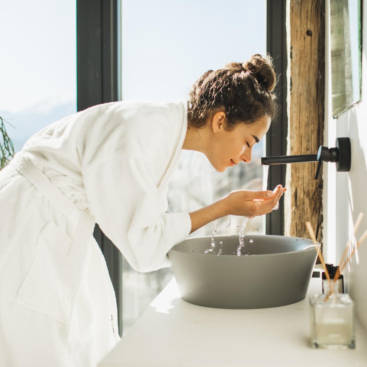  woman with acne washing her face 