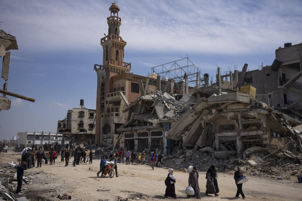 Palestinians walk through the destruction in the wake of an Israeli air and ground offensive in Khan Younis, southern Gaza Strip, Monday, April 8, 2024. Israel says it has withdrawn its last ground troops from the city, ending a four-month operation. (AP Photo/Fatima Shbair)