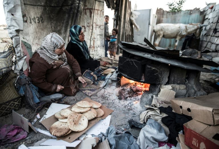 Palestinian women bake bread next to their makeshift home in the Khan Yunis refugee camp in the southern Gaza Strip on April 19, 2017