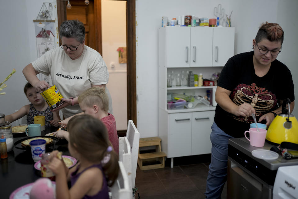 Russian nationals Anna Domini, left, and her wife Anastasia, prepare breakfast for their children, in their home in Buenos Aires, Argentina, Saturday, April 22, 2023. After a little more than a year living in Argentina, “we’re absolutely used to our status of married women and that we are parents of lots of kids and that we can be free here,” without having to worry about somebody could “take our kids” or “take us to prison,” Anastasia Domini said. Russia explicitly outlawed same-sex marriages in 2020. (AP Photo/Natacha Pisarenko)