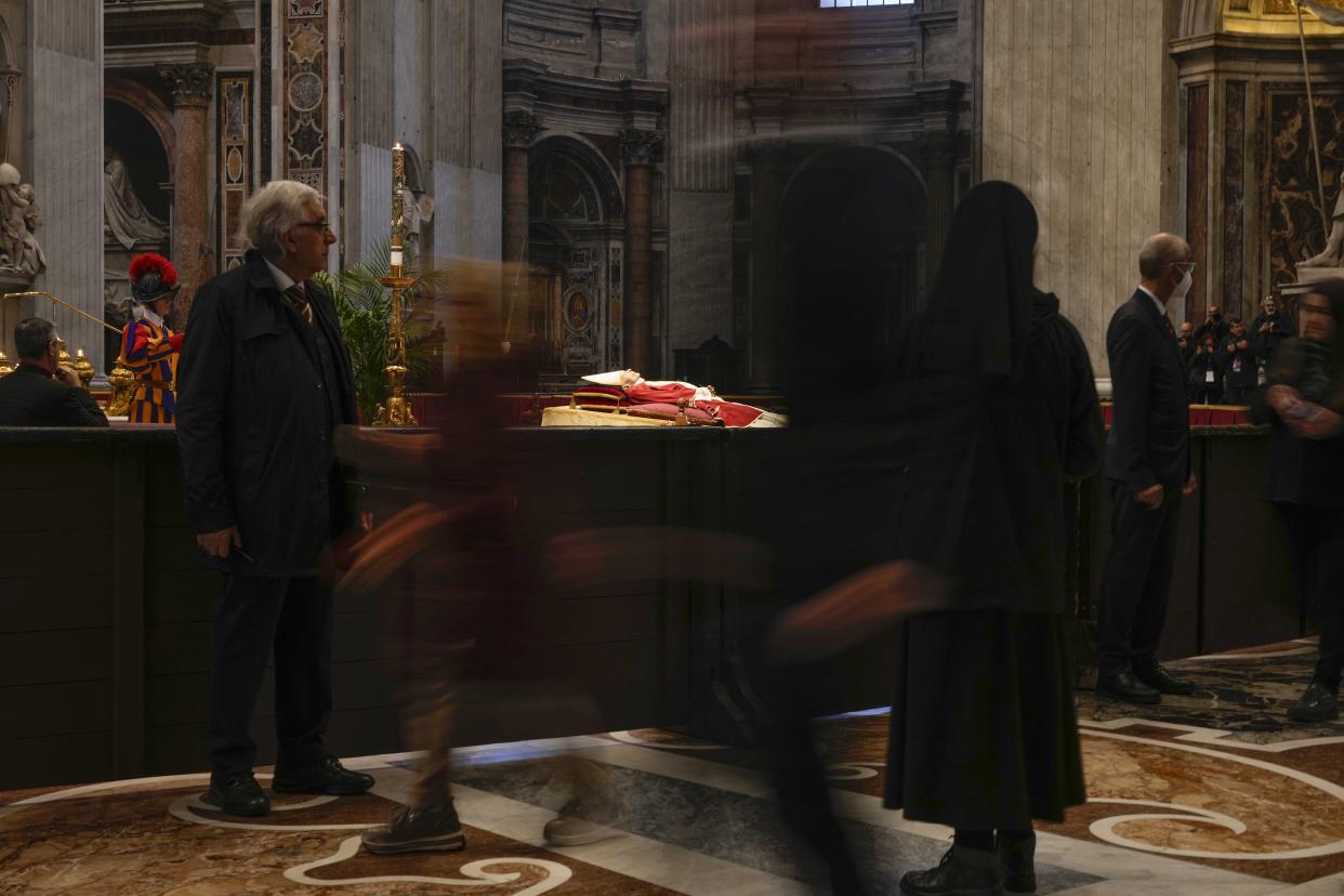 People look at the body of late Pope Emeritus Benedict XVI laid out in state inside St. Peter's Basilica at The Vatican, Monday, Jan. 2, 2023. Benedict XVI, the German theologian who will be remembered as the first pope in 600 years to resign, has died, the Vatican announced Saturday. He was 95. (AP Photo/Andrew Medichini)