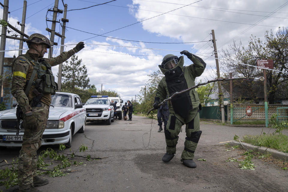 A de-miner wearing protective gear works in an area where unexploded devices were found after shelling of Russian forces in Maksymilyanivka, Ukraine, Tuesday, May 10, 2022. (AP Photo/Evgeniy Maloletka)