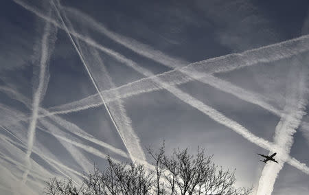 FILE PHOTO: A passenger plane flies through aircraft contrails in the skies near Heathrow Airport in west London, April 12, 2015. REUTERS/Toby Melville/File Photo