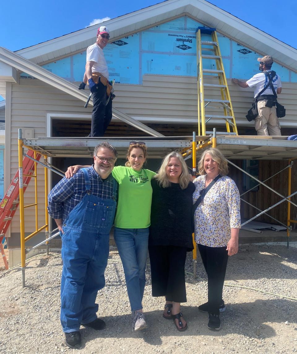 Abby Newman, second from left, poses in front of a new Habitat for Humanity home that is being built for her in Sturgeon Bay. Also pictured, from left, are Jimmy Kaplan, Jacinda Duffin and Laurie Flanagan, with Paul Zeller and David Diller in background installing siding.