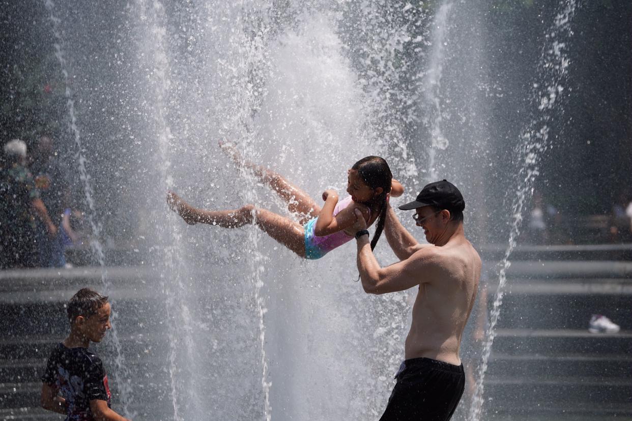 People cool down at a fountain on Washington Square Park in New York, on July 19, 2019. 