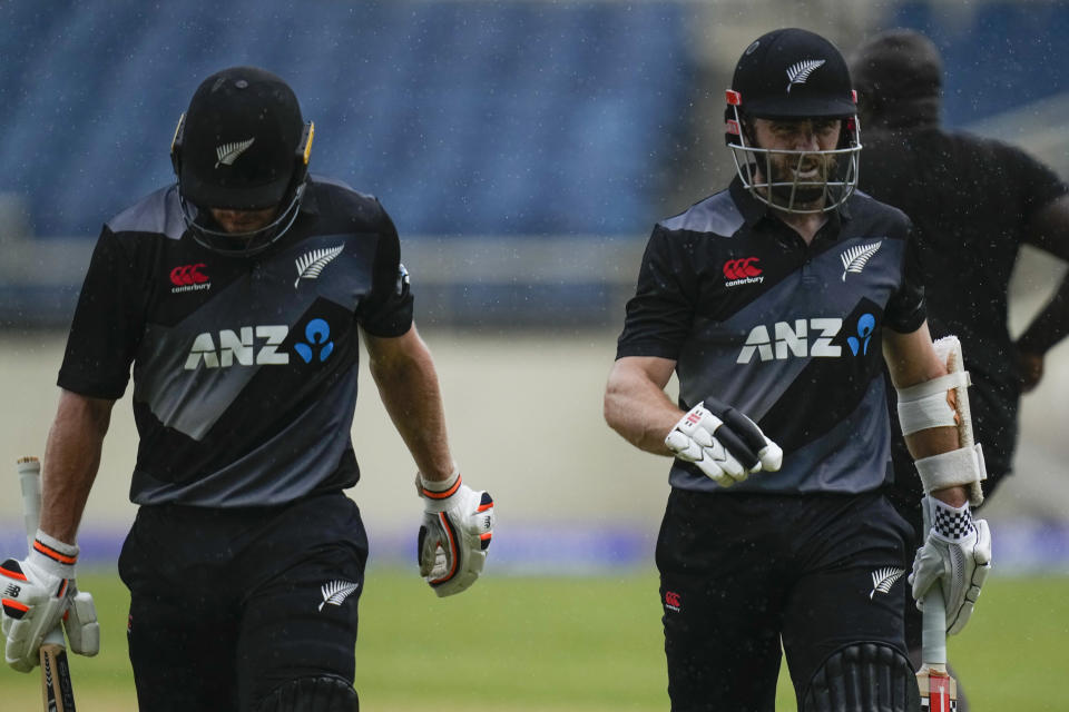 New Zealand's captain Kane Williamson, right, and teammate Glenn Phillips leave the field as rain stops play during their first T20 cricket match against West Indies at Sabina Park in Kingston, Jamaica, Wednesday, Aug. 10, 2022. (AP Photo/Ramon Espinosa)