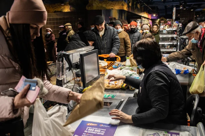 Shoppers line up to pay for their items at a supermarket. 