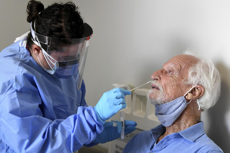 National Institutes of Health-funded Moderna COVID-19 vaccine study participant ￼William Webb, right, gets a COVID-19 nose swab test by University of Miami Miller School of Medicine nurse Loreta Padron, Wednesday, Sept. 2, 2020 in Miami. Miami is one of 89 cities around the U.S. that's testing the Moderna COVID-19 vaccine. (AP Photo/Taimy Alvarez)