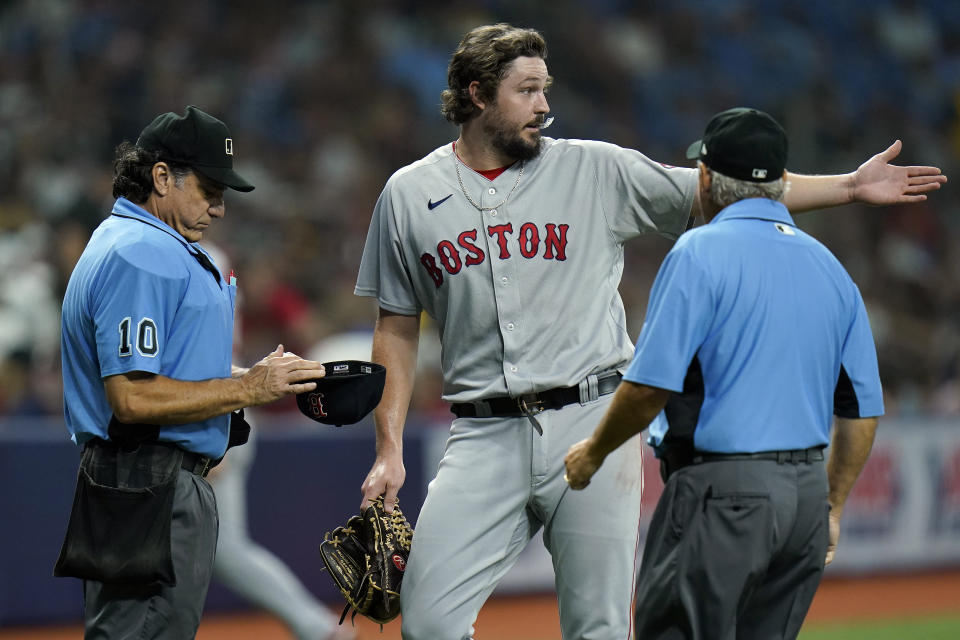 Boston Red Sox relief pitcher Josh Taylor gestures as home plate umpire Phil Cuzzi (10) checks his hat for any foreign substances after Taylor retired the Tampa Bay Rays during the seventh inning of a baseball game Tuesday, June 22, 2021, in St. Petersburg, Fla. Looking on is umpire Tom Hallion. (AP Photo/Chris O'Meara)