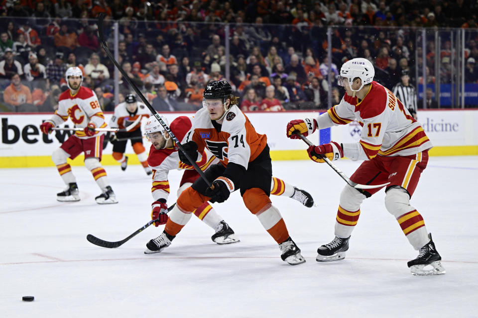 Philadelphia Flyers' Owen Tippett, center, skates for the puck between the defense of Calgary Flames' Nick DeSimone (57) and Yegor Sharangovich (17) during the second period of an NHL hockey game, Saturday, Jan. 6, 2024, in Philadelphia. (AP Photo/Derik Hamilton)