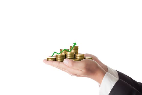 A man holding out his hands with coins and a chart showing growth sitting in them.