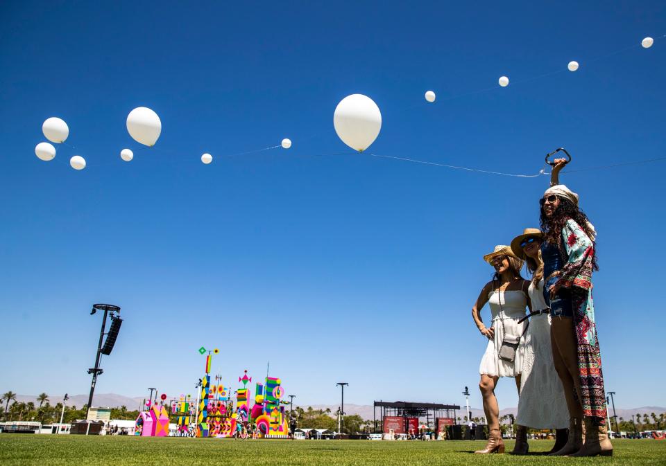 Festivalgoers take a turn holding up the end of the balloon line during the Coachella Valley Music and Arts Festival in Indio, Calif., Friday, April 12, 2024.