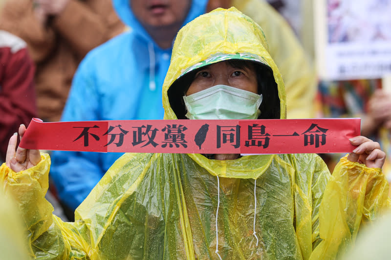 立法院28日續審國會改革法案，場外雨勢不斷，民眾身穿雨衣持標語「不分政黨 同黨一命」，表達訴求。（中央社）