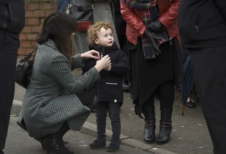 The grandson of Martin McGuinness, Dulta, has his coat adjusted during McGuinness's funeral at St Columba's Church in Londonderry, Northern Ireland, March 23, 2017. REUTERS/Clodagh Kilcoyne