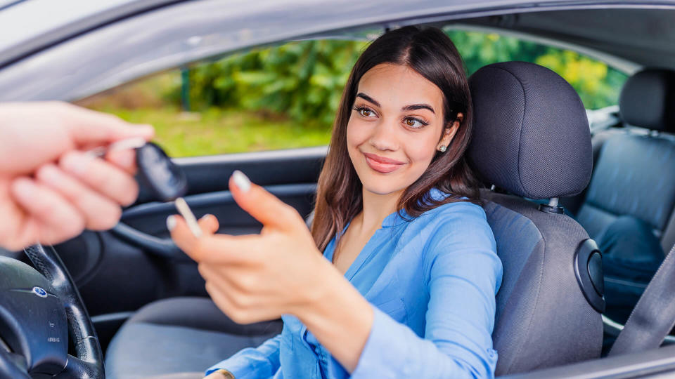 Young woman receiving the keys of her new car.