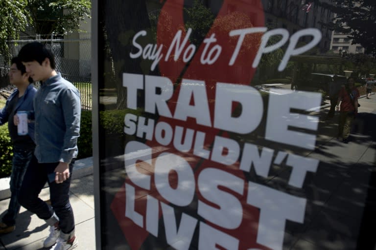 People pass an advertisement protesting the passage of the Trans-Pacific Partnership in Washington, DC on July 23, 2015